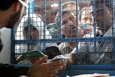 Palestinians gather at a counter of the warehouse of the United Nations Relief Works Agency, as they wait to receive a food ticket