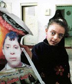 A small paralyzed girl holds a poster of her young cousin.